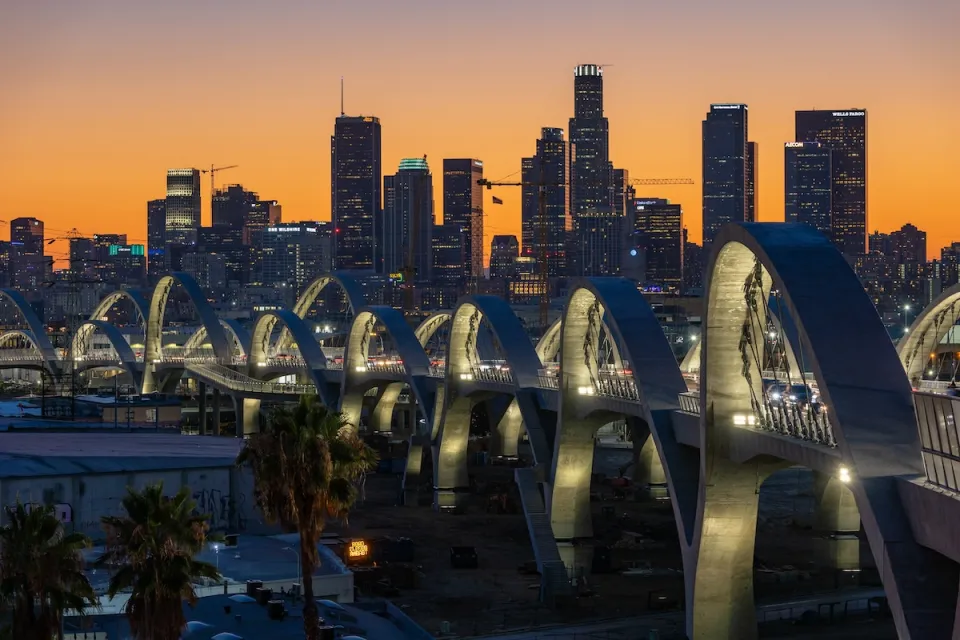 Downtown Los Angeles skyline at sunset with new 6th Street Viaduct arches in foreground.